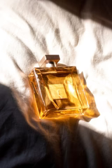 golden bottle of perfume on a white bed sheet